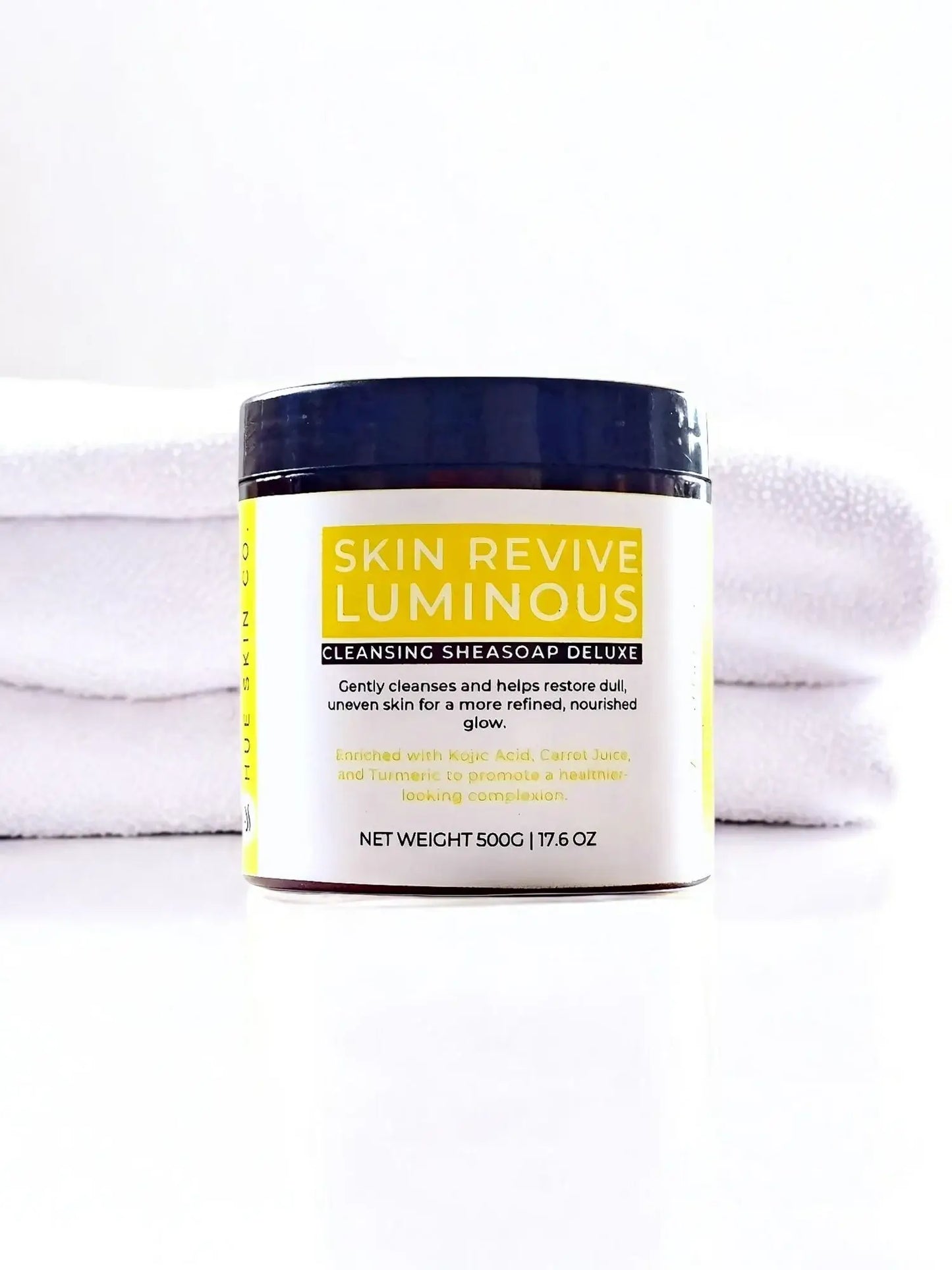 Skin Revive Luminous Sheasoap Deluxe jar placed on a white towel for skincare renewal and even tone.