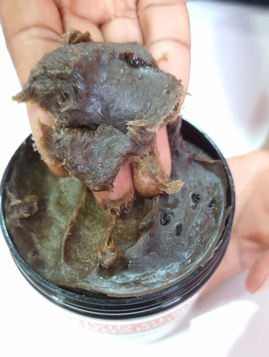 VIVID GLOW GLOW BLACK SOAP DELUXE OFFER shown being applied from jar, highlighting its rich texture.